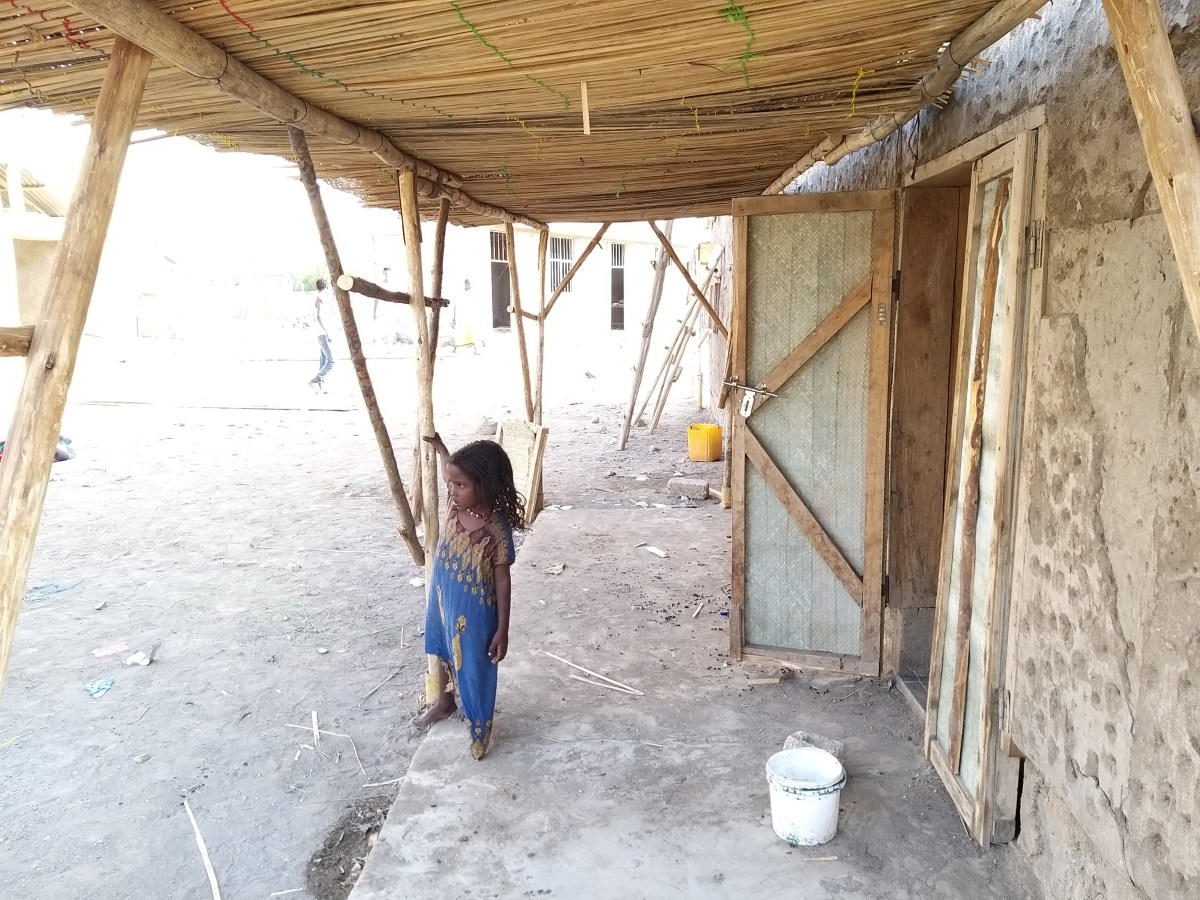 A child standing near a hostel doorway